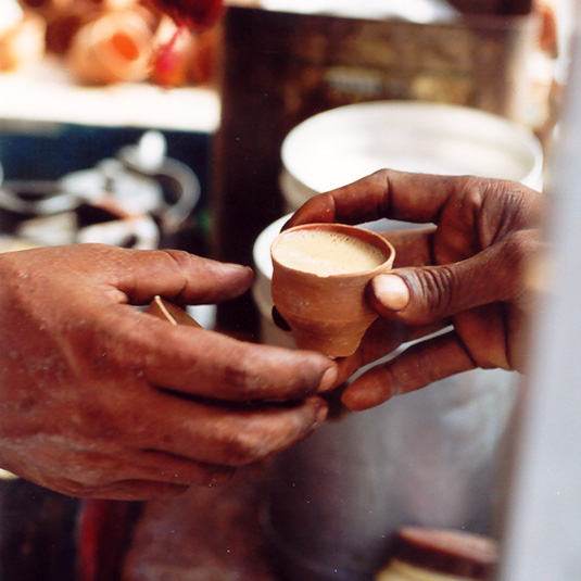 A hand is giving a small cup of tea